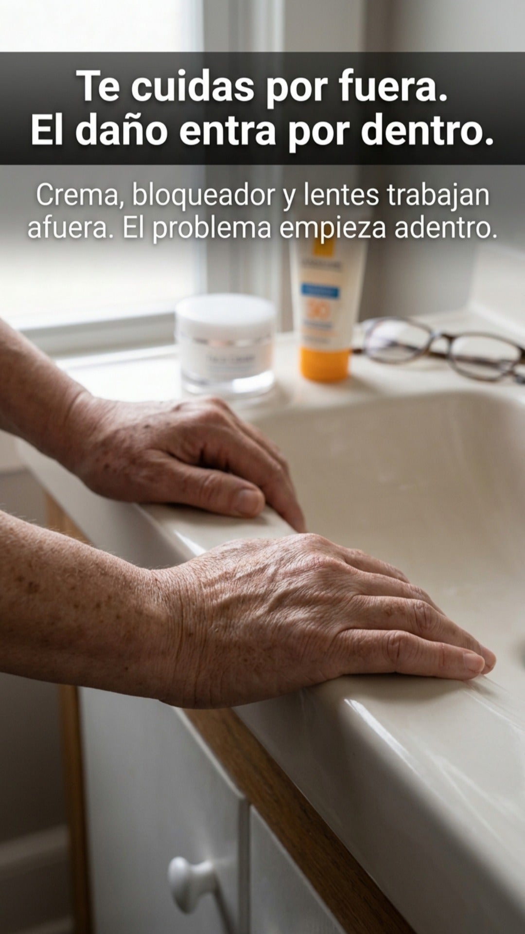 Manos con manchas de la edad sobre el lavamanos, junto a la crema y el bloqueador